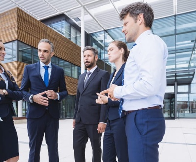 Website Migration Services: Business Professionals Collaborating Outside a Modern Corporate Building During a Strategic Discussion on Digital Transformation and Website Infrastructure Migration.