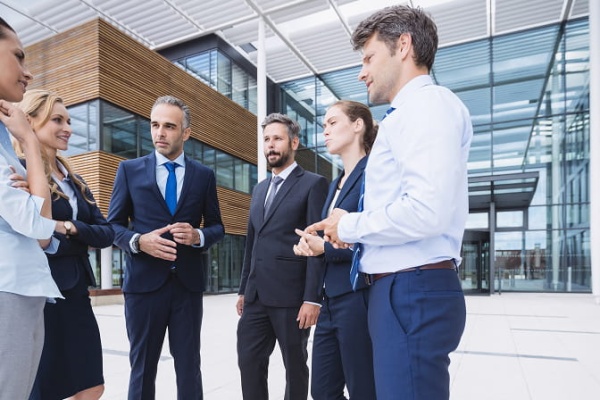 Website Migration Services: Business Professionals Collaborating Outside a Modern Corporate Building During a Strategic Discussion on Digital Transformation and Website Infrastructure Migration.