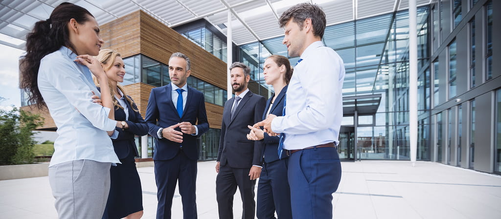 website-migration-services-a-business-priority Website Migration Services: Business Professionals Collaborating Outside a Modern Corporate Building During a Strategic Discussion on Digital Transformation and Website Infrastructure Migration.